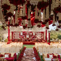 A view of the 'Laal Ishq' wedding ceremony setup from the guest's perspective. The combination of hanging floral strings, a rich red backdrop, and traditional seating created an immersive and culturally rich experience.