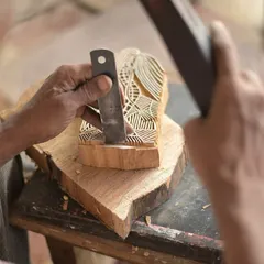 The hands of a master carver translating a historic lino design from the Bábbarra Women's Centre into a teak woodblock. This cross-cultural exchange is a beautiful example of how craft can bridge languages and continents.