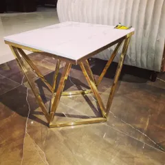 This corner table is designed to add a touch of glamour to any space. It features a geometric stainless steel base with a gold PVD finish, topped with a pristine white marble slab for a luxurious look.
