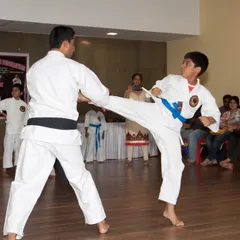 A demonstration of a basic sparring drill, where a student practices a front kick against an instructor. This is fundamental to building timing and distance for kumite.
