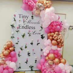 For a beautiful baby girl's celebration, this pink and rose gold balloon arch is a fantastic choice. The backdrop, with its "Tiny Miracle Endless Love" message and scattered roses, adds a sweet and personal touch to the baby shower decor.