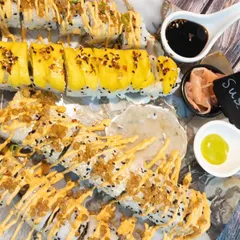 An overhead view of a beautifully arranged sushi platter, showcasing different types of rolls drizzled with spicy mayo and topped with crispy bits.