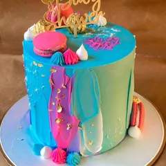 A vibrant and artistic cake perfect for a modern baby shower. The colorful buttercream strokes, gold leaf accents, and macaron decorations create a festive and celebratory look.