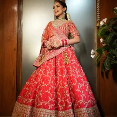 A full view of a classic bridal look. The hair is styled into a traditional bun, providing a graceful foundation that supports the dupatta and enhances the overall silhouette of the bridal lehenga.