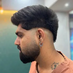 This modern mullet features a high fade on the sides, leaving length and texture on top and at the back. It's a bold style that combines the sharpness of a fade with the flow of a longer cut.