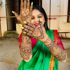 A happy bride posing with her full bridal mehndi, which features her and her partner's initials.
