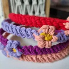 A stack of colorful macrame headbands, showing the variety of shades available. The combination of the main band and the flower accent can be customized to your liking.