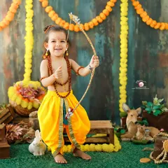 Celebrating culture with a 'Little Ram' photoshoot. This toddler looks joyful and strong, dressed in traditional attire and holding a bow and arrow, set against a vibrant, festive backdrop.