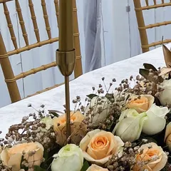 A detail shot focusing on the high-quality fresh flowers and delicate baby's breath used in the table runner, set against the elegant gold Chiavari chairs.