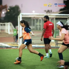 A coach observes closely as a player executes a drill during a girls-only session. This focused attention is key to individual player development and technical refinement.