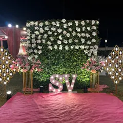 A personalized photo spot with the couple's initials in marquee lights. The backdrop is a beautiful wall of white flowers, creating an elegant and custom feature.