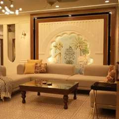 A living room designed with a blend of modern and traditional Indian elements. It features an L-shaped sofa, a classic wooden coffee table, and a stunning arched wall niche with custom artwork.