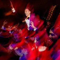 A motion-blur shot of the groom being lifted on shoulders on the dance floor. This artistic technique captures the high energy and excitement of the Sangeet party.