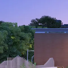 The contrast of textures is a key element in our design. Here, the hard edge of a brick wall meets the soft, organic forms of a sculptural fence and surrounding trees.