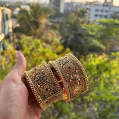 A pair of broad, intricately designed bridal bangles or 'tode'. This photo, taken in natural light, shows the beautiful floral motifs and coloured stone work.