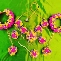 A vibrant and colorful floral jewelry set perfect for a lively Mehendi or Haldi function. This set features a beautiful combination of pink, yellow, and purple flowers, and includes a necklace, hathphools, earrings, and a maang tikka.