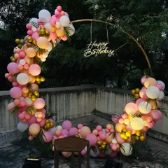 A different perspective of the circular ring backdrop on a terrace. The lush green trees in the background provide a natural contrast to the bright pink and gold balloons.