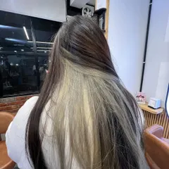 A peekaboo or under-layer color, with a bright blonde section hidden beneath the natural dark hair. It's a playful and trendy look.