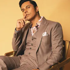 Actor Randeep Hooda in a classic, thoughtful pose. The warm tones of the suit and background create a timeless feel for this celebrity portrait.