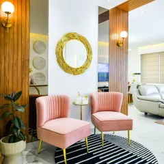 This entrance nook draws you in with its soft blush chairs, warm wood paneling, and a statement gold mirror. The combination of textures and colors creates a space that feels open, airy, and quietly elegant.