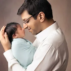 A father's love, so gentle and strong. He holds his tiny newborn, sharing a quiet moment of connection that beautifully illustrates the new bond being formed.
