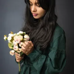 A soft and contemplative moment captured during a portrait session. The way she holds the flowers adds a touch of gentleness and introspection to this classic studio portrait.