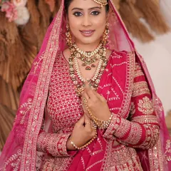 This stunning bridal ensemble showcases a layered necklace set, including a long rani haar, which adds a majestic touch to the intricate pink lehenga.