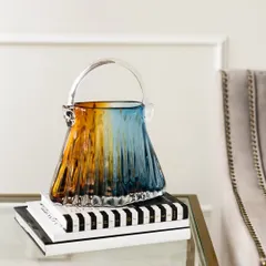 This unique handblown glass showpiece is shaped like a handbag, with a beautiful blend of amber and blue hues. It's a whimsical and artistic piece of table decor that is sure to catch the eye.