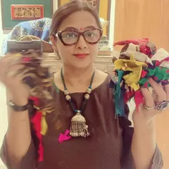 Me in my studio, holding bundles of colorful fabric scraps. These are the building blocks for my improv quilts, each one a precious piece of a future story.