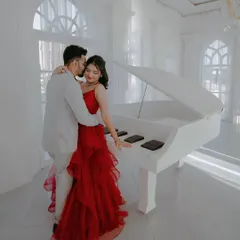 A fairytale moment with a couple by a grand white piano, the bride in a stunning red gown. This shows how I can create elegant and classic romance in a studio setting.