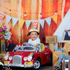 This little one is ready to hit the road in a shiny red toy car, part of our wood cafe and camping theme. A perfect shot for an adventurous first birthday.