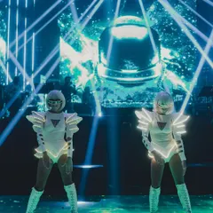 A closer look at the futuristic LED dancers on a stage designed with an astronaut helmet backdrop and piercing blue laser lights. Every element is thematically cohesive.