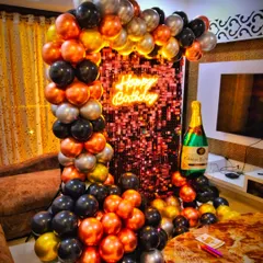 I designed this stylish birthday setup for an adult celebration, featuring a shimmering sequin wall as the backdrop. The balloon arch uses a modern color palette of metallic orange, black, and silver, complemented by a neon sign and a large champagne bottle prop.