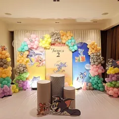 A fun-filled "Tom and Jerry" themed second birthday party. The decor includes character cut-outs, themed pedestals for the cake, and a colorful balloon arch.