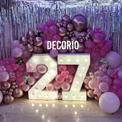 For a dazzling party vibe, I used a silver foil curtain as a backdrop. The large light-up '27' numbers are the main focus, surrounded by a lush arrangement of pink and metallic balloons.