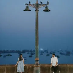 The magic of Mumbai at dusk provides a cinematic setting for romance. This shot at the Gateway of India uses the moody blue hour and iconic lamppost to frame the couple, creating a sense of quiet intimacy within the bustling city.