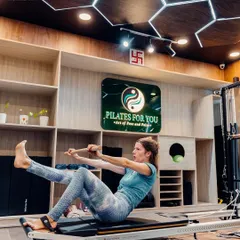 This client is using the push-through bar on the reformer for a full-body exercise that strengthens the core and improves coordination. The studio's calming ambiance enhances focus.