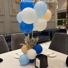 Even the tables get a special touch. This is a simple yet elegant table centerpiece with blue, white, and beige balloons and a bit of dried pampas grass, matching the event's overall theme.