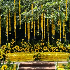 A beautiful Haldi seating area set against a natural green backdrop. We used hanging marigold strings and beds of sunflowers to create a vibrant, sunny atmosphere.