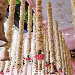 For a traditional touch, I created a ceiling installation of hanging floral garlands, known as 'latkans', made from white flowers and accented with pink carnations and brass bells.