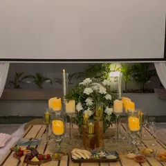 The romantic tablescape for the proposal dinner. We included a beautiful floral centerpiece, dozens of candles, a cheese board, and a projector screen for a personal slideshow.