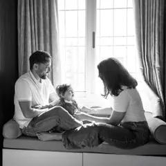 Sometimes the most powerful family portraits are the quiet ones. This black and white photo captures a moment of peace and connection by the window, a timeless memory created in the comfort of their own home.