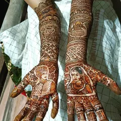 A clear view of a completed bridal portrait mehendi. I take great care to capture the likeness of the bride and groom, surrounded by traditional wedding symbols like the shehnai and kalash.