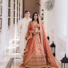 Proving that you don't have to wear red to be a stunning bride. For this couple, we chose a gorgeous rust Sabyasachi lehenga and coordinated the groom's look in a complementary ivory, creating a regal and modern aesthetic for their daytime ceremony.