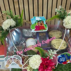 A beautiful Teej festival hamper for a client. It includes traditional bangles, body butter, perfume, and other cosmetics, decorated with 'Happy Teej' tags.