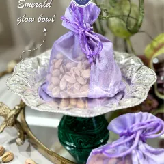 The Emerald Glow Bowl, seen here with a 'potli' of pistachios. This silver-coated bowl with an emerald green base is a perfect blend of tradition and luxury.