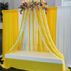 A unique canopy-style seating arrangement for a Haldi ceremony. I created this look with cascading garlands of yellow and white flowers flowing from a floral crown, providing a beautiful and immersive space for the bride or groom.