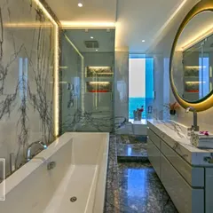 This bathroom is a sanctuary crafted from floor-to-ceiling marble. We integrated a freestanding bathtub, a glass-enclosed shower, and a custom vanity with backlit mirrors to create a space that feels like a private, five-star spa.