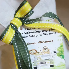 A personalized thank you tag for a jungle-themed first birthday, complete with a matching green and yellow ribbon.