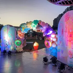 The Candyland entrance archway, beautifully lit up as the sun sets, creating a magical and inviting atmosphere for the guests.